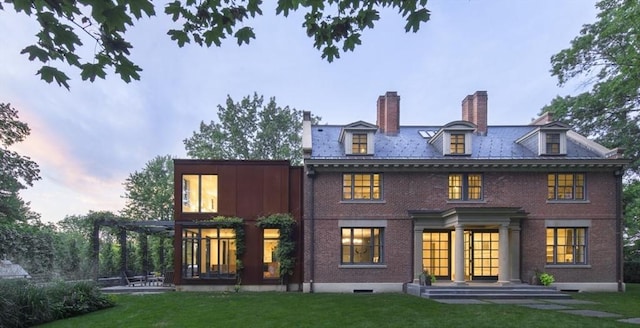 55 Fayerweather St, Cambridge, MA 02138 - back of house at dusk with brick siding, a chimney, a lawn, and a patio area