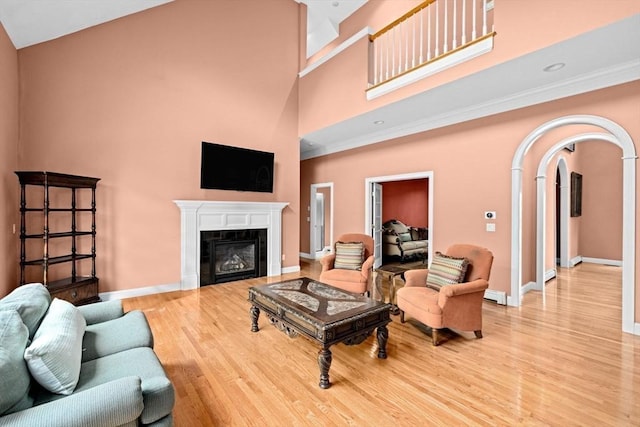 15 Henrys Ln, Norwell, MA 02061 - living room featuring a towering ceiling, light wood-type flooring, arched walkways, baseboards, and a tile fireplace