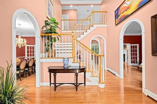 15 Henrys Ln, Norwell, MA 02061 - foyer entrance featuring a baseboard heating unit, arched walkways, wood finished floors, crown molding, and stairs