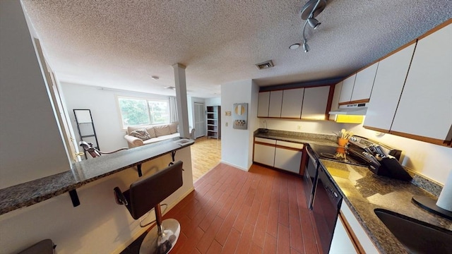 35 Prospect St Unit 309, Woburn, MA 01801 - kitchen featuring under cabinet range hood, dark wood finished floors, open floor plan, a breakfast bar, and a textured ceiling