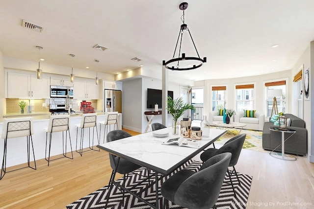 dining space featuring a notable chandelier and light hardwood / wood-style floors