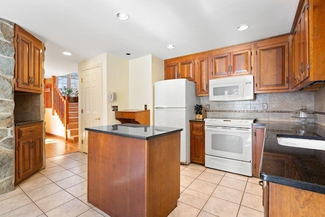 kitchen featuring tasteful backsplash, light tile patterned floors, white appliances, and a center island