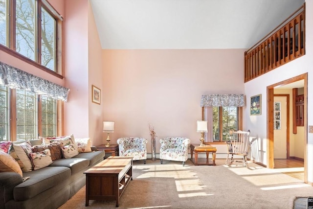 carpeted living room with a baseboard heating unit and a high ceiling