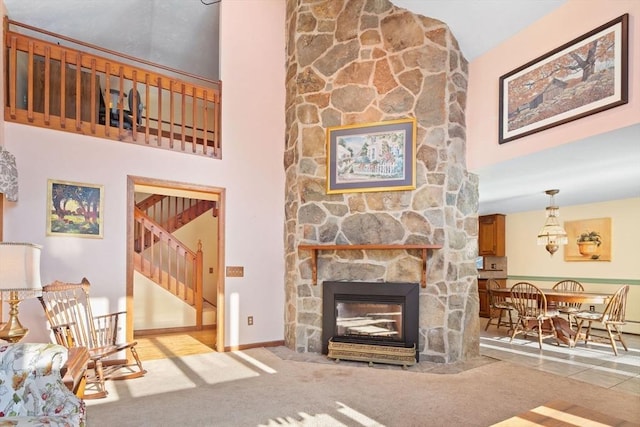 carpeted living room featuring a stone fireplace and a towering ceiling