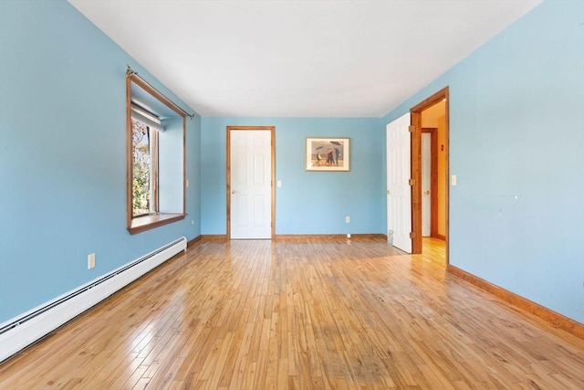 empty room with light hardwood / wood-style floors and a baseboard heating unit