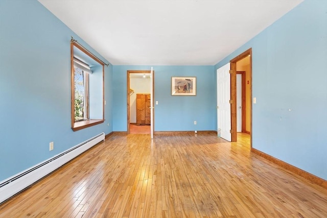 unfurnished room featuring a baseboard radiator and light wood-type flooring