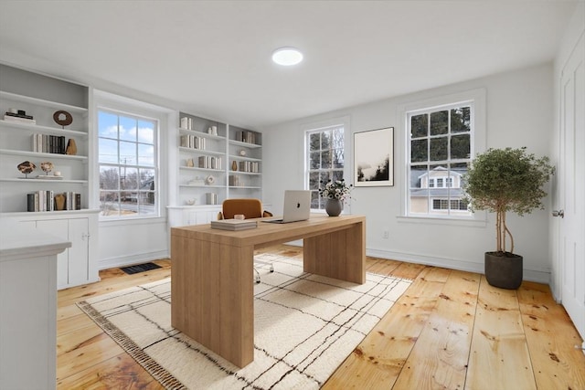 office area featuring light wood-type flooring and built in features