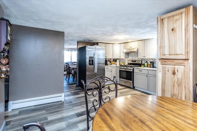 kitchen featuring tasteful backsplash, stainless steel appliances, wood-type flooring, and a baseboard heating unit