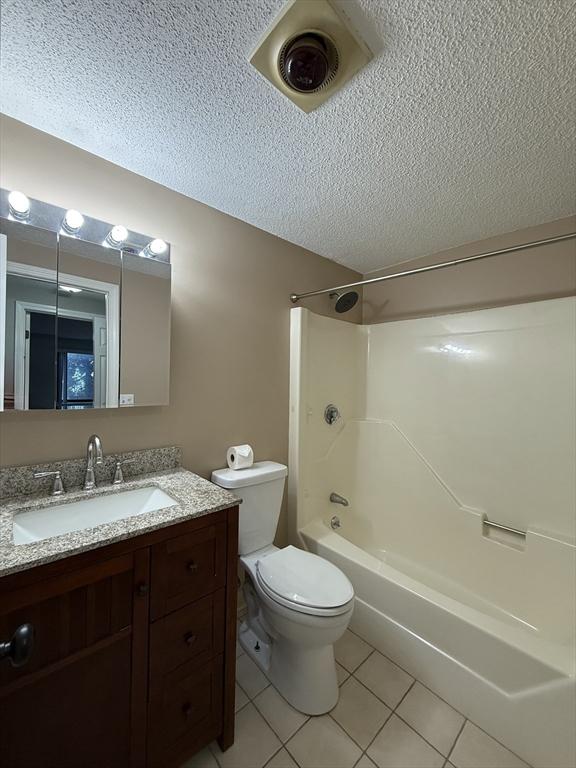 30 Revere Beach Pkwy Unit 116, Medford, MA 02155 - bathroom with tile patterned floors, a textured ceiling, toilet, vanity, and  shower combination