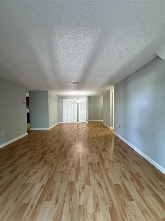 30 Revere Beach Pkwy Unit 116, Medford, MA 02155 - unfurnished living room with wood finished floors, baseboards, and a textured ceiling