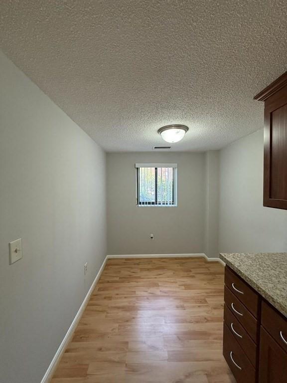 30 Revere Beach Pkwy Unit 116, Medford, MA 02155 - unfurnished dining area with light wood-style floors, baseboards, and a textured ceiling