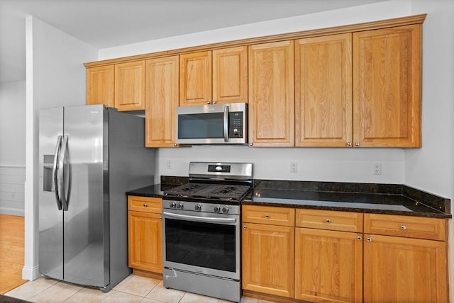 kitchen with dark stone countertops, light tile patterned floors, and stainless steel appliances