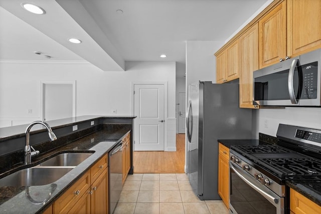 kitchen with light tile patterned floors, stainless steel appliances, sink, and dark stone countertops