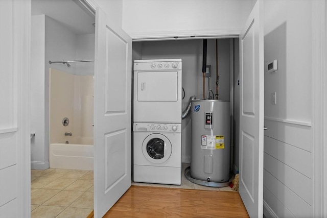 washroom with stacked washer / drying machine, tile patterned floors, and electric water heater