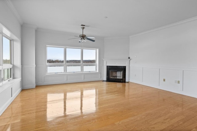 unfurnished living room with ornamental molding, a water view, ceiling fan, and light hardwood / wood-style floors