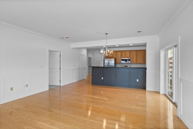 kitchen with appliances with stainless steel finishes, decorative light fixtures, a notable chandelier, and light hardwood / wood-style flooring