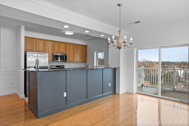 kitchen featuring stainless steel appliances, pendant lighting, light hardwood / wood-style floors, and kitchen peninsula