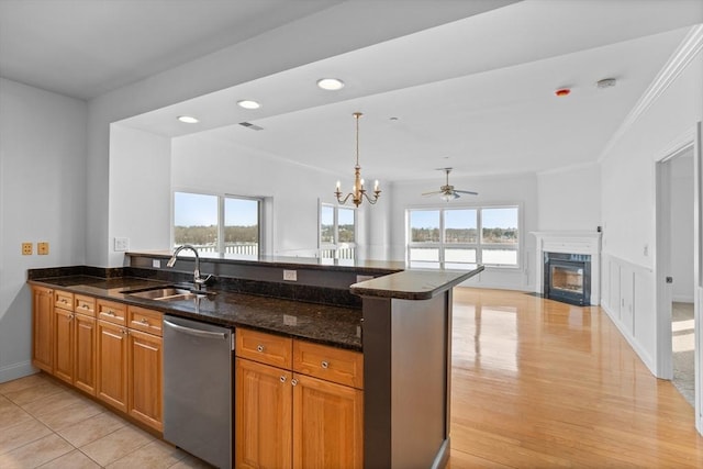 kitchen with sink, kitchen peninsula, dark stone counters, and dishwasher