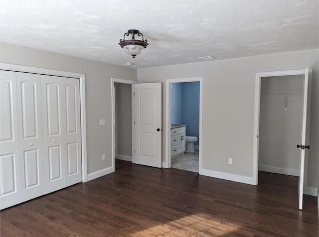 unfurnished bedroom featuring connected bathroom and dark hardwood / wood-style floors