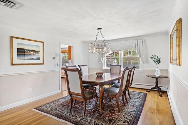 dining space featuring light wood finished floors, a wealth of natural light, visible vents, and baseboard heating