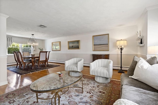 living area with wood finished floors, a notable chandelier, visible vents, baseboard heating, and a baseboard radiator