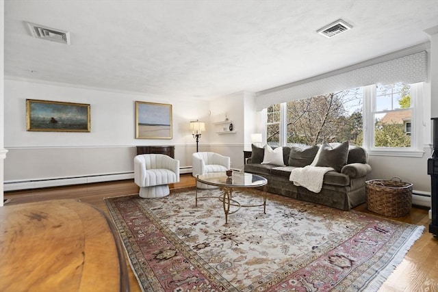 living room featuring a baseboard heating unit, a healthy amount of sunlight, visible vents, and wood finished floors