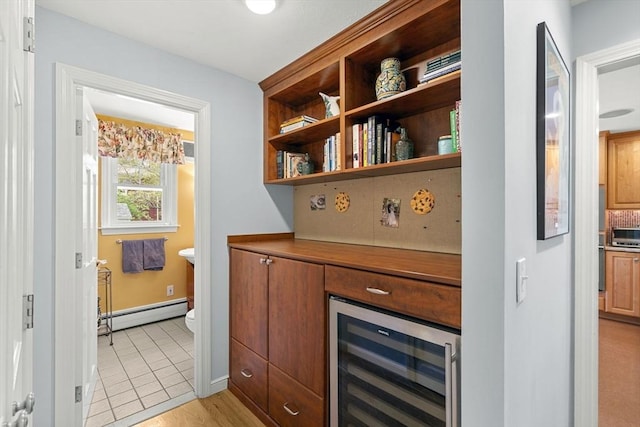 bar with wine cooler, a baseboard radiator, baseboards, and light wood-type flooring