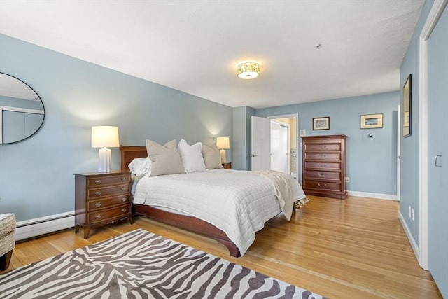 bedroom featuring light wood finished floors, baseboards, and a baseboard heating unit