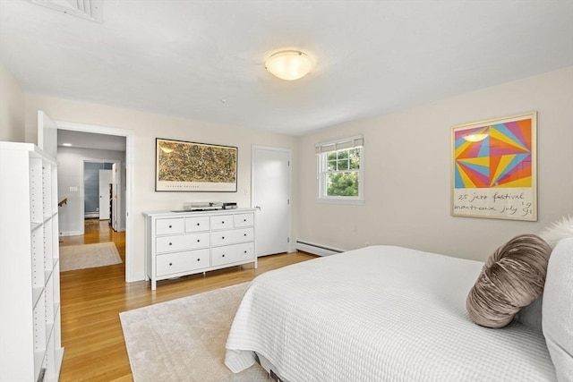 bedroom with baseboards, light wood-style flooring, and a baseboard radiator