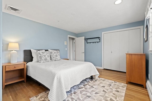 bedroom featuring baseboards, light wood-style flooring, and visible vents
