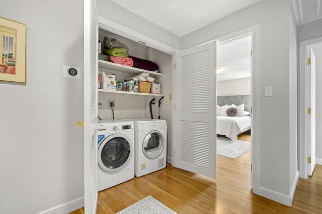 laundry room featuring washer and clothes dryer, laundry area, baseboards, and light wood-type flooring