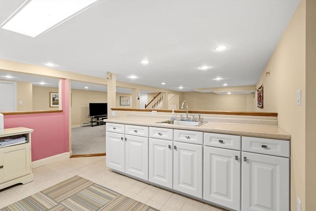 kitchen featuring recessed lighting, baseboards, a sink, white cabinetry, and light countertops