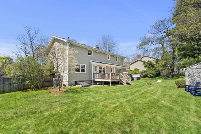 back of house featuring a deck, a lawn, and a fenced backyard