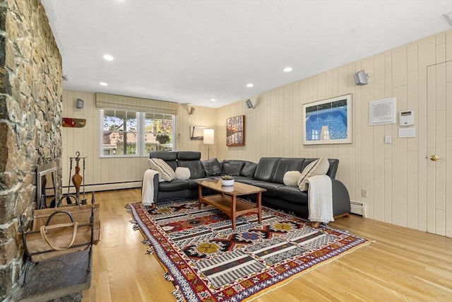 living room featuring wood walls, wood finished floors, and baseboard heating