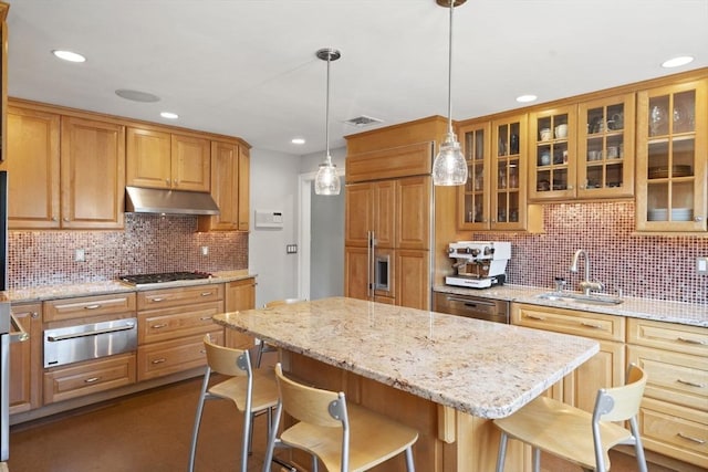 kitchen featuring under cabinet range hood, a breakfast bar, visible vents, a sink, and a warming drawer