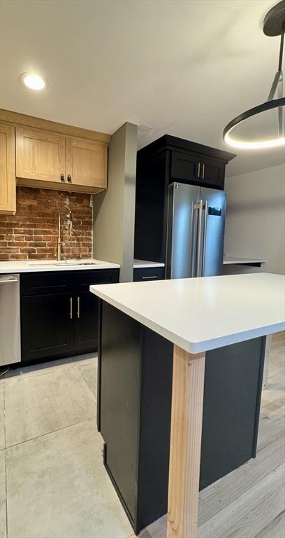191 W Canton Unit 1, Boston, MA 02116 - kitchen featuring stainless steel appliances, a sink, light countertops, a kitchen island, and dark cabinets