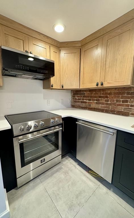191 W Canton Unit 1, Boston, MA 02116 - kitchen featuring appliances with stainless steel finishes, range hood, light countertops, and light tile patterned floors