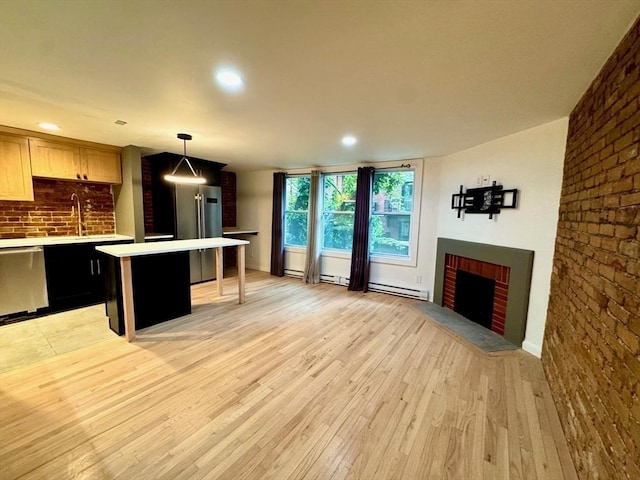 191 W Canton Unit 1, Boston, MA 02116 - kitchen with appliances with stainless steel finishes, light countertops, light wood-style floors, a brick fireplace, and a kitchen island
