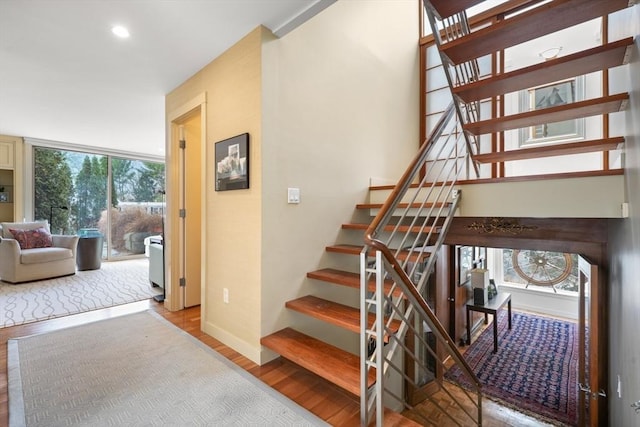 stairs with baseboards, wood finished floors, and recessed lighting