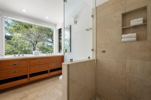 bathroom featuring double vanity, a stall shower, a sink, and toilet