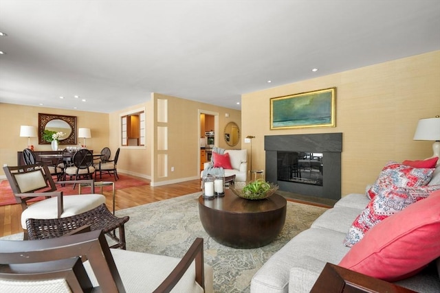 living room with recessed lighting, baseboards, wood finished floors, and a glass covered fireplace