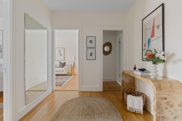 hallway with light wood-type flooring and baseboards