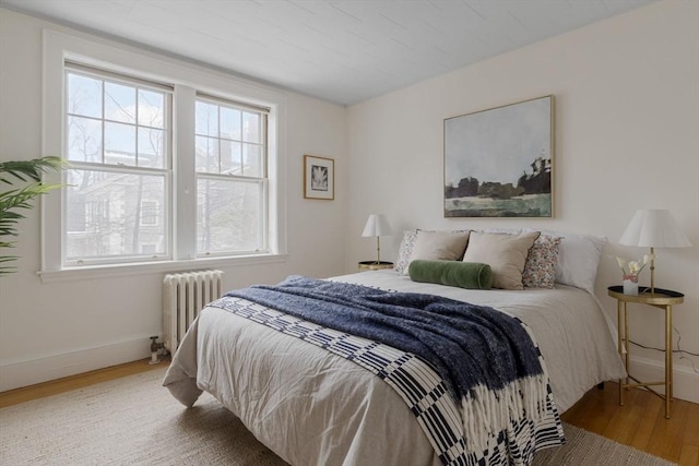 bedroom with radiator, baseboards, and wood finished floors