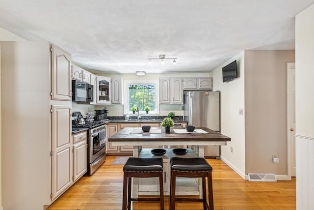 2 Strawstone Ln, Norton, MA 02766 - kitchen featuring appliances with stainless steel finishes, a breakfast bar, dark countertops, light wood-style floors, and a sink