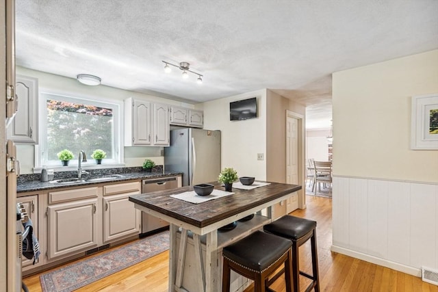 2 Strawstone Ln, Norton, MA 02766 - kitchen with stainless steel appliances, a sink, light wood-type flooring, a kitchen breakfast bar, and a wainscoted wall