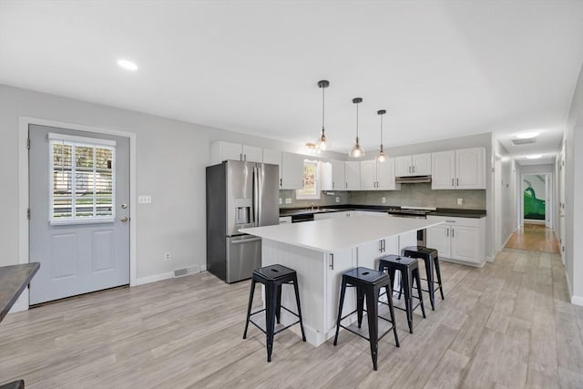 kitchen featuring visible vents, white cabinets, a kitchen bar, and stainless steel fridge with ice dispenser
