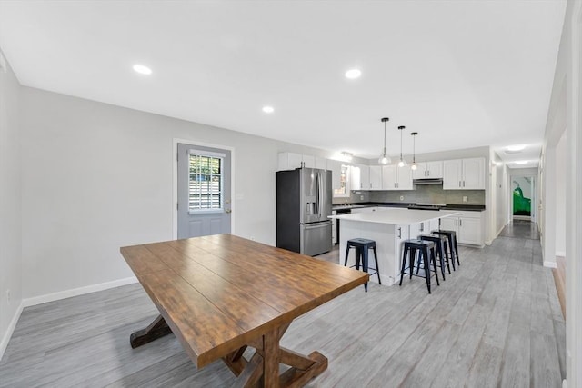 dining space featuring baseboards, recessed lighting, and light wood finished floors