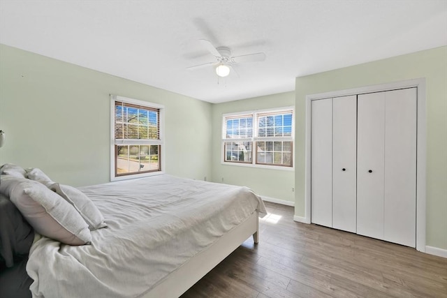 bedroom with a ceiling fan, baseboards, wood finished floors, and a closet