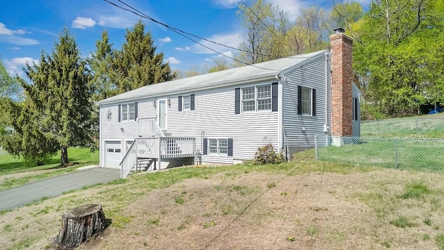 view of front of home with driveway, a chimney, a garage, fence, and a front lawn