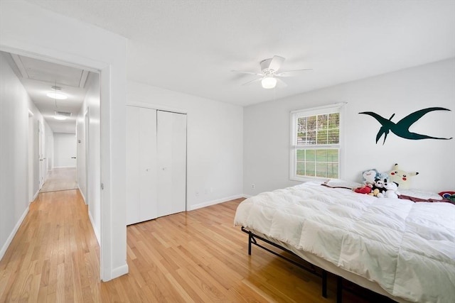 bedroom with baseboards, attic access, light wood-style flooring, and a closet